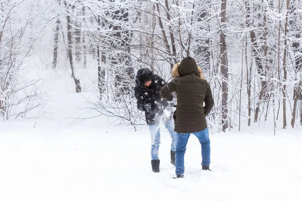 Mode de vie, saison et concept de loisirs - Couple drôle jouant boule de neige dans le parc d'hiver — Photo