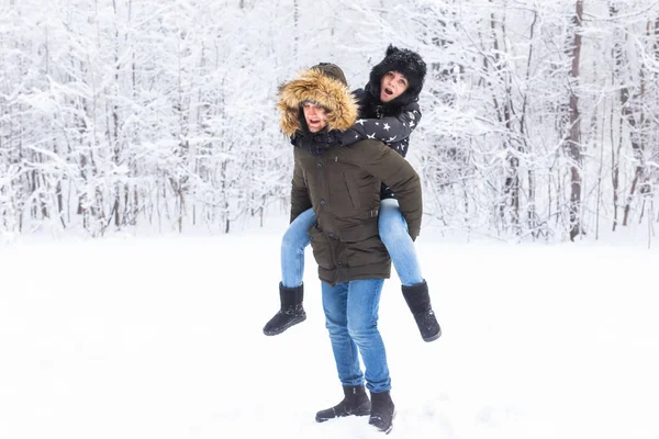 Retrato de jovem casal feliz no parque de inverno com seu amigo por trás — Fotografia de Stock