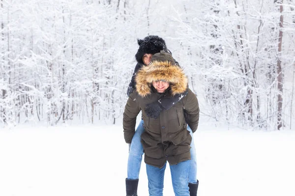 Retrato de jovem casal feliz no parque de inverno com seu amigo por trás — Fotografia de Stock