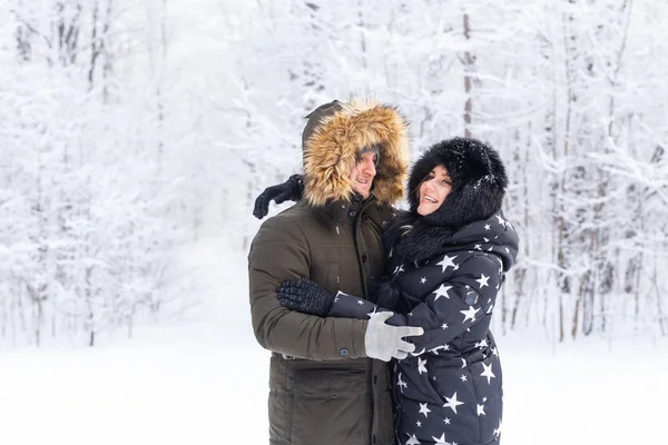 Jonge verliefde echtparen hebben plezier in het besneeuwde bos. Actieve wintervakanties. — Stockfoto