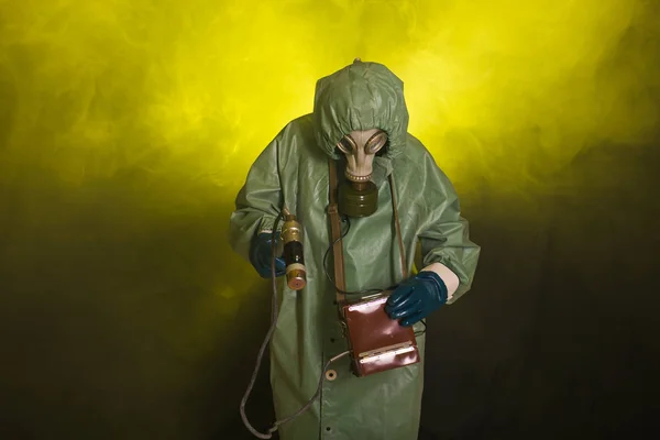 Koncept radiace, znečištění a nebezpečí - Muž v ochranném oděvu a plynové masce na tmavém pozadí — Stock fotografie