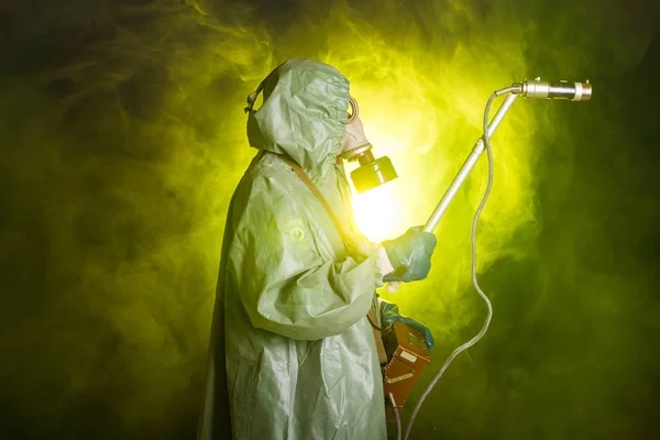 Radiation, pollution and danger concept - Man in protective clothing and a gas mask on a dark background