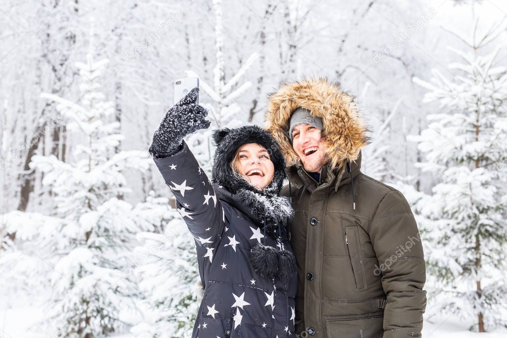 Season and relationship concept - Funny couple taking selfie in the winter time