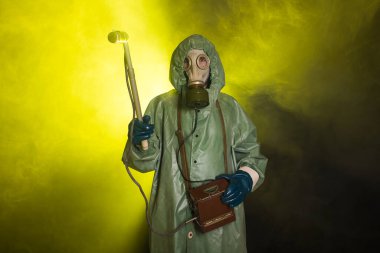 Radiation, pollution and danger concept - Man in protective clothing and a gas mask on a dark background clipart