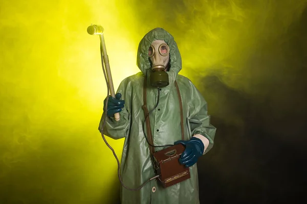 Radiation, pollution and danger concept - Man in protective clothing and a gas mask on a dark background