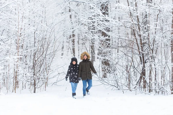 Νεαρό ζευγάρι περπατά σε ένα χιονισμένο πάρκο. Χειμερινή περίοδος. — Φωτογραφία Αρχείου