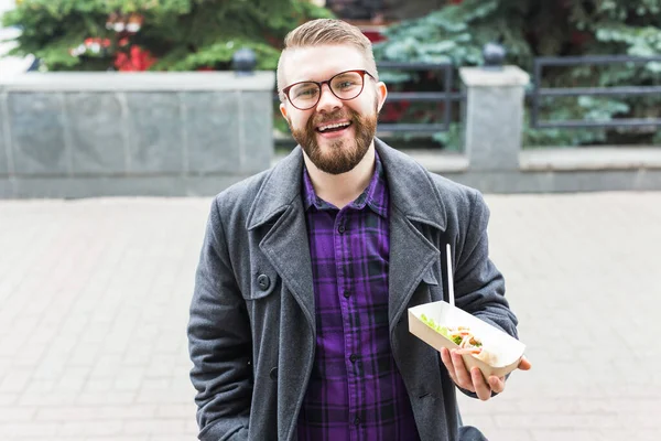 Comida chatarra, comer y el concepto de estilo de vida - joven con comida come en la calle de la ciudad . — Foto de Stock