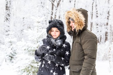 Teknoloji ve ilişki konsepti mutlu bir çiftin kış ormanında selfie çekmesi.