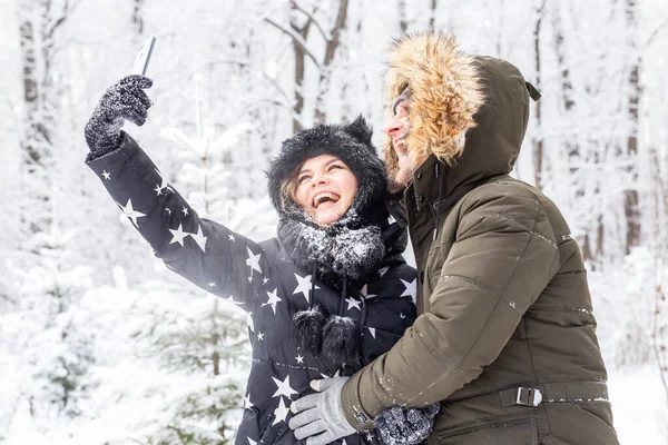 Säsong och relation koncept - Roligt par tar selfie på vintern — Stockfoto
