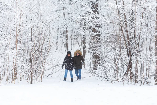 Jeune couple marchant dans un parc enneigé. Saison d'hiver. — Photo