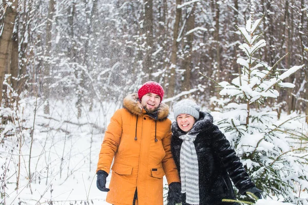 Amour, saison, amitié et concept de personnes - jeune homme et femme heureux s'amuser et jouer avec la neige dans la forêt d'hiver — Photo