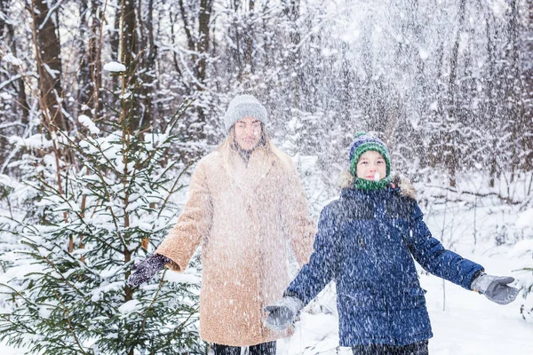 Rodzicielstwo, zabawa i koncepcja sezonu - szczęśliwa matka i syn bawią się i bawią się śniegiem w zimowym lesie — Zdjęcie stockowe