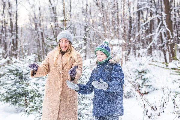 Parenting, fun et concept de saison - Bonne mère et son fils s'amusent et jouent avec la neige dans la forêt d'hiver — Photo