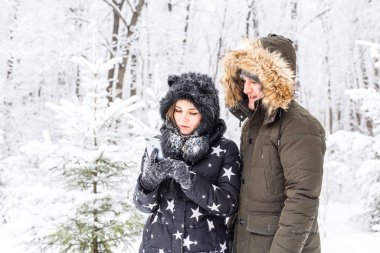 Teknoloji ve ilişki konsepti mutlu bir çiftin kış ormanında selfie çekmesi.