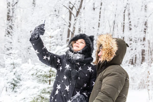 Technologie i koncepcja relacji - Szczęśliwa uśmiechnięta para robi selfie w zimowym lesie na zewnątrz — Zdjęcie stockowe