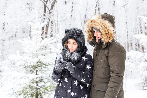 Technologies et concept de relation - Couple souriant heureux prenant un selfie dans une forêt d'hiver à l'extérieur — Photo