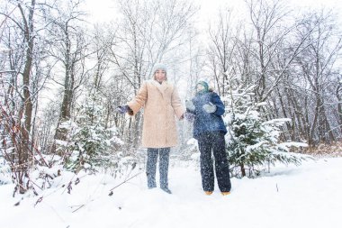 Ebeveynlik, eğlence ve sezon konsepti - Mutlu anne ve oğul kış ormanlarında kar ile oynayıp eğleniyorlar