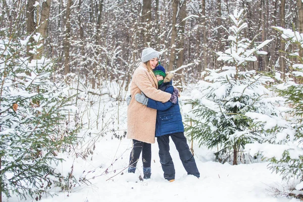 Conceito de paternidade, diversão e temporada - Mãe e filho felizes se divertindo e brincando com a neve na floresta de inverno — Fotografia de Stock