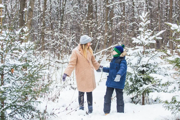 Conceito de paternidade, diversão e temporada - Mãe e filho felizes se divertindo e brincando com a neve na floresta de inverno — Fotografia de Stock