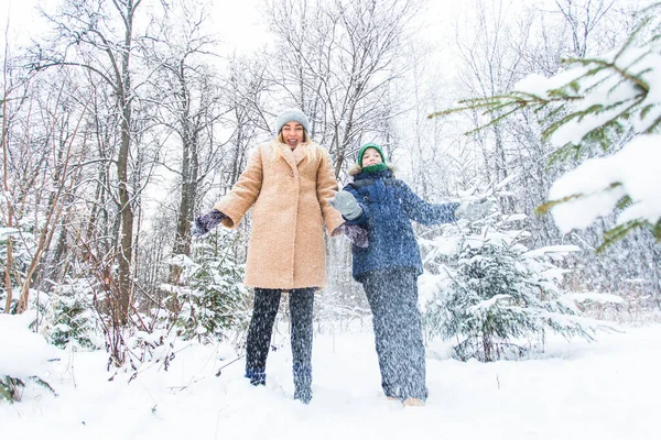 Parenting, fun et concept de saison - Bonne mère et son fils s'amusent et jouent avec la neige dans la forêt d'hiver — Photo