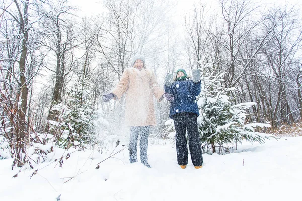 Parenting, fun et concept de saison - Bonne mère et son fils s'amusent et jouent avec la neige dans la forêt d'hiver — Photo