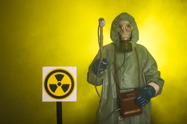 Radyasyon, kirlilik ve tehlike kavramı - koruyucu giysiler içinde bir adam ve karanlık arka planda bir gaz maskesi