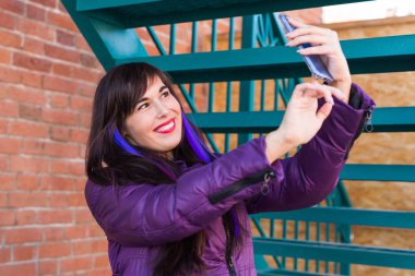 Teknoloji, şehir ve insanlar konsepti - uzun saçlı güzel kız çatıda selfie çekiyor