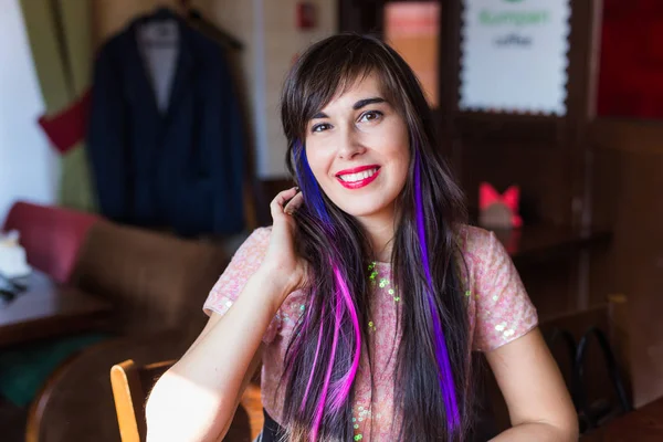 Jonge stijlvolle trendy vrouw met multi-gekleurde streng in het haar zit in cafe — Stockfoto