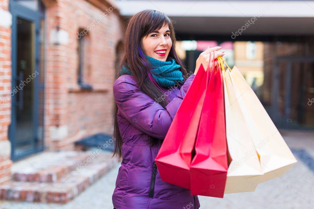 Shopping, consumer and sales concept - Beautiful woman holding many shopping bags on a city street