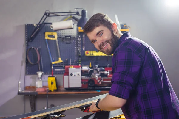 Conceito de reparo, serviço e pessoas - um homem reparando o esqui esfregando uma parafina — Fotografia de Stock