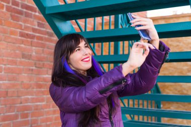 Teknoloji, şehir ve insanlar konsepti - uzun saçlı güzel kız çatıda selfie çekiyor