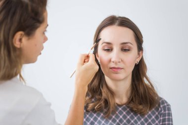 Güzellik ve kozmetik konsepti - Makyaj sanatçısı genç bir kadından profesyonel makyaj yapıyor