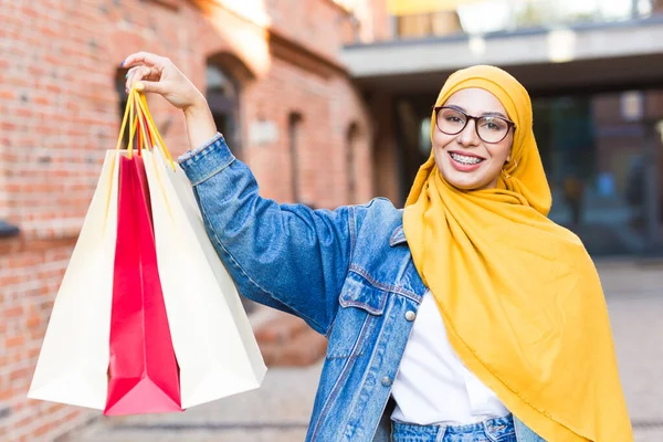 Eladó és vételi koncepció - Boldog arab muszlim lány bevásárlószatyrokkal bevásárlóközpont után — Stock Fotó