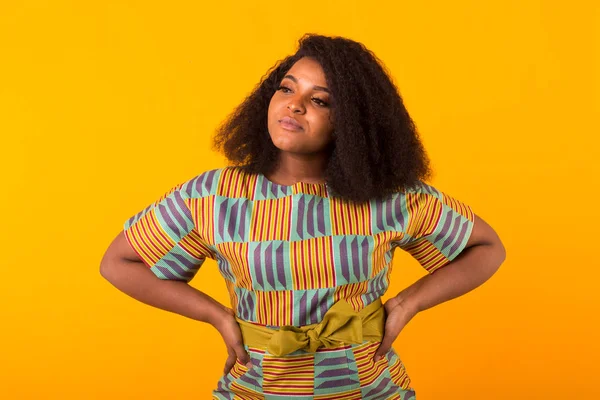 Young beautiful african american girl with an afro hairstyle. Portrait on yellow background.