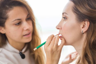 Güzellik ve kozmetik konsepti - Makyaj sanatçısı genç bir kadından profesyonel makyaj yapıyor