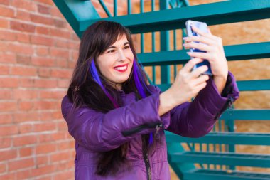 Teknoloji, şehir ve insanlar konsepti - uzun saçlı güzel kız çatıda selfie çekiyor