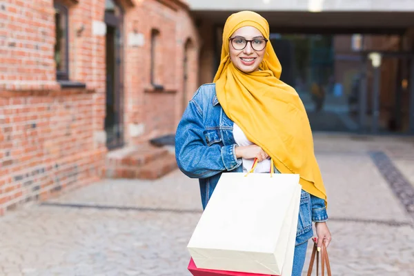 Kauf- und Verkaufskonzept - Glückliches arabisches muslimisches Mädchen mit Einkaufstüten nach Einkaufszentrum — Stockfoto