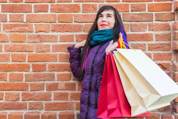 Einkaufs-, Konsum- und Verkaufskonzept - Schöne Frau mit vielen Einkaufstüten über Backsteinmauer-Hintergrund auf einer Stadtstraße — Stockfoto