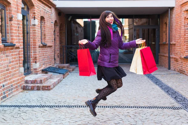 Einkaufs-, Konsum- und Verkaufskonzept - Lustige junge Frau springt mit vielen Einkaufstüten auf einer Stadtstraße — Stockfoto