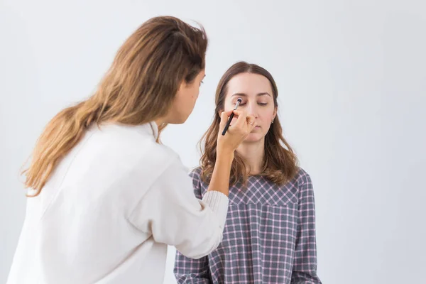 Schönheits- und Kosmetikkonzept - Visagistin macht professionelles Make-up für junge Frau — Stockfoto