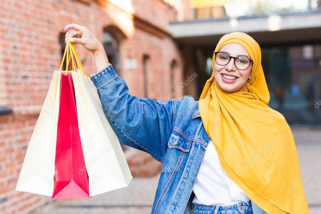 Sale and buying concept - Happy arab muslim girl with shopping bags after mall