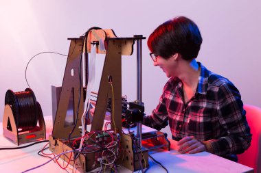 Teknoloji ve mühendislik konsepti - Laboratuvarda çalışan kadın mühendis, 3D yazıcı bileşenlerini ayarlıyor.