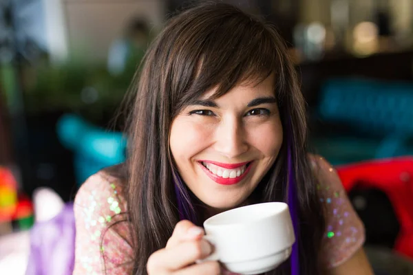 Portret van jonge stijlvolle trendy vrouw met veelkleurige streng in haar zit in cafe met kopje thee — Stockfoto