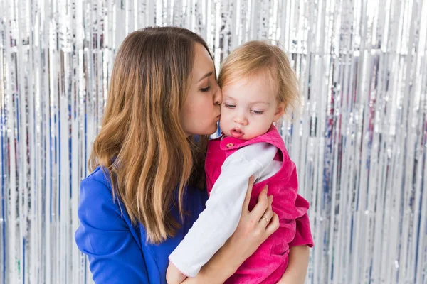 Infância, férias e conceito de família - Mãe beijando a filha do bebê em fundo brilhante. Close-up — Fotografia de Stock