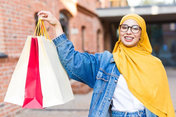 Kauf- und Verkaufskonzept - Glückliches arabisches muslimisches Mädchen mit Einkaufstüten nach Einkaufszentrum — Stockfoto