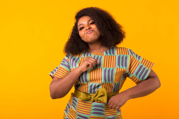 Young beautiful african american girl with an afro hairstyle. Portrait on yellow background. Girl looking at camera.