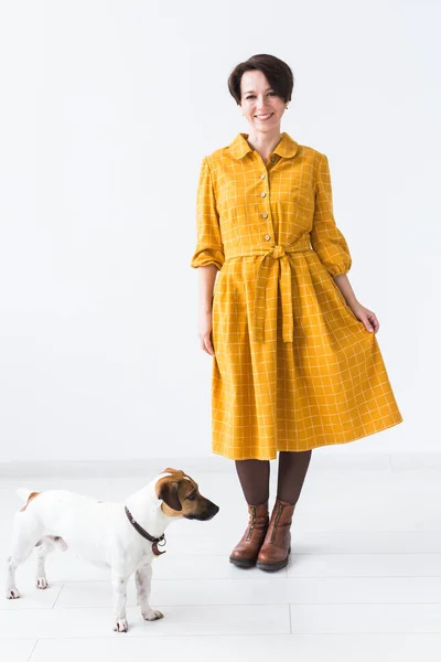 Vrolijke jonge vrouw poserend in een gele jurk met haar geliefde hond Jack Russell Terrier op een witte achtergrond. Het concept van casual wear en huisdieren — Stockfoto