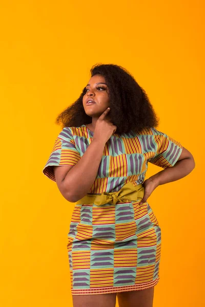 Young beautiful african american girl with an afro hairstyle. Portrait on yellow background. Girl looking at camera.