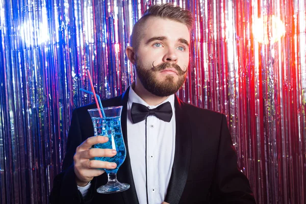 Club party en vakantie concept - Portret van elegante knappe man in een duur pak houdt blauwe cocktail op glanzende achtergrond. — Stockfoto