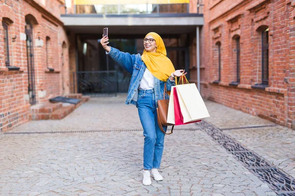 Verkauf, Technologien und Kaufkonzept - Glückliche arabische Muslimin macht nach dem Einkaufen Selfie im Freien — Stockfoto